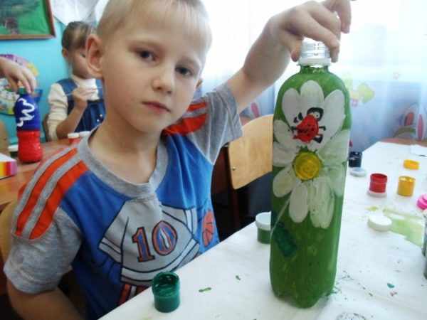 Мальчик держит раскрашенную бутылку