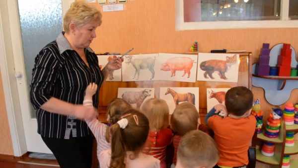 Воспитательница показывает детям животных на картинках