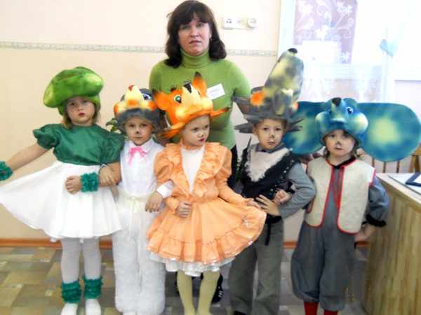 Воспитатель стоит рядом с детьми в театральных костюмах