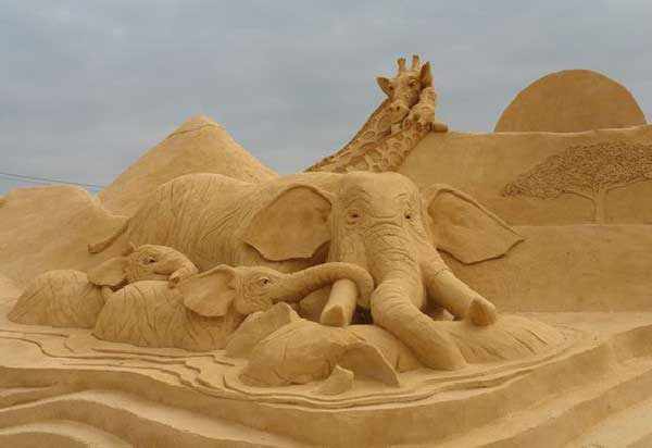 Фигуры слонов и жирафов из песка