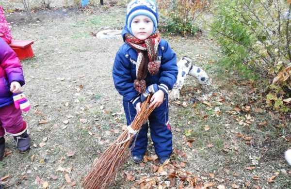 Мальчик подметает осенние листья