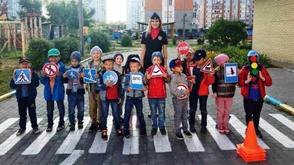 Дети стоят на пешеходном переходе со знаками ПДД в руках