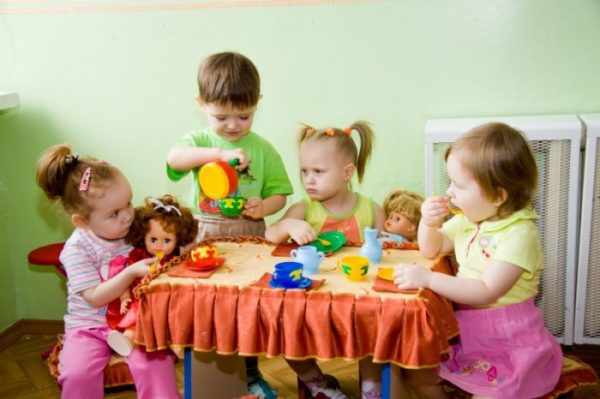 Дети играют вместе с куклами в чаепитие