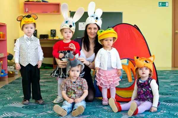 Воспитательница в шапочке с ушками зайца и дети в шапочках зайца, мышки, лисы, лягушки и медведя
