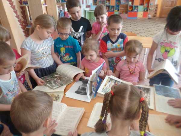 Дети у стола рассматривают книги, картинки о войне