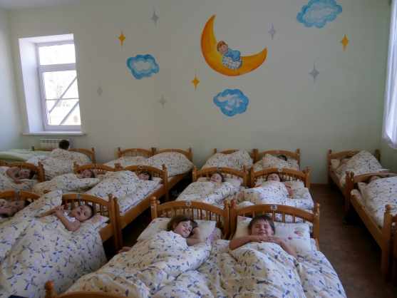 Дети спят в кроватках, на стене аппликация луны