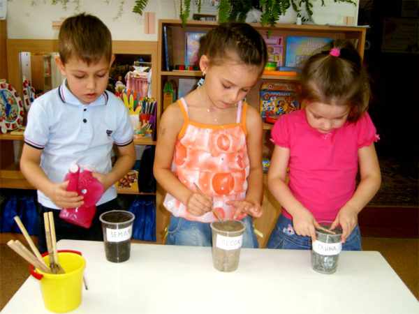 Трое детей проводят эксперименты с песком, землёй, водой и глиной