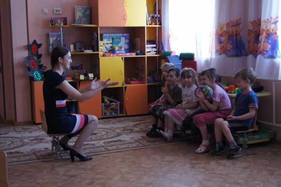 Педагог показывает упражнение сидящим напротив детям