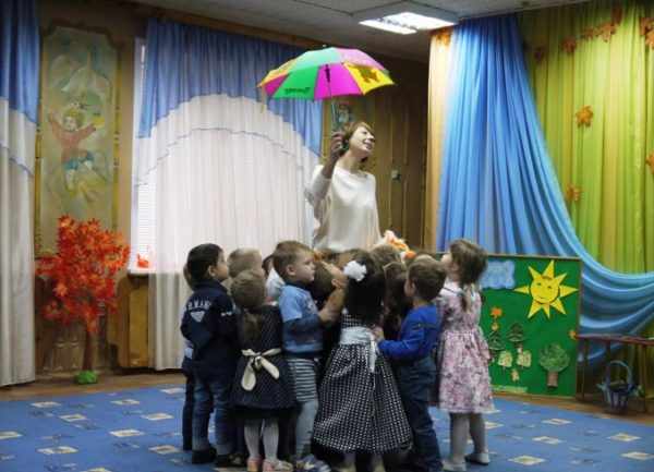 Дети вокруг воспитательницы с зонтом