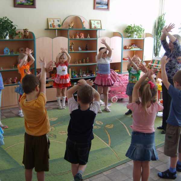 Дети и воспитатель стоят с поднятыми вверх руками