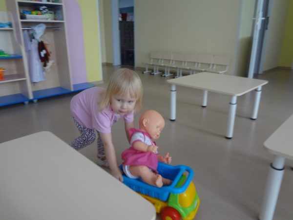 Девочка везёт куклу на игрушечной машине