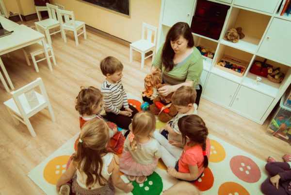 Дети сидят вокруг педагога, держащего в руках куклу