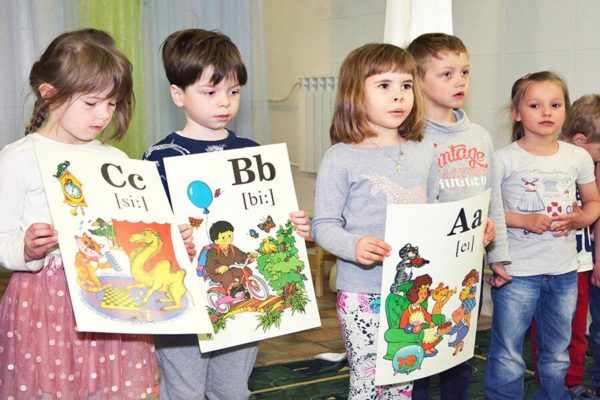 Дети держат картинки с английскими буквами