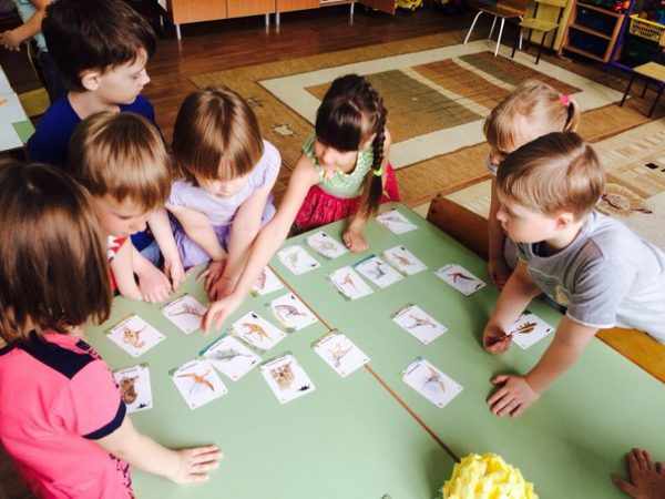 Дети раскладывают на столах карточки с изображениями динозавров