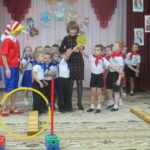 Команды детей с красными и синими галстуками и Буратино на физкультурном празднике