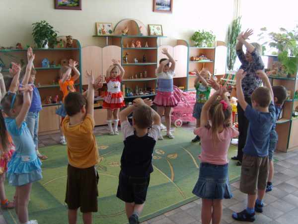 Дети и педагог стоят в кругу, подняв руки верх