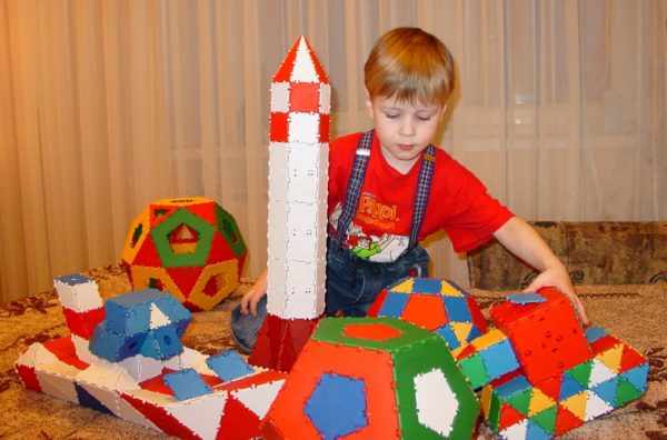 Мальчик играет с ракетой, кораблём и шарами из крупного конструктора