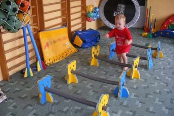 Мальчик в красной футболке в спортзале бежит через препятствия