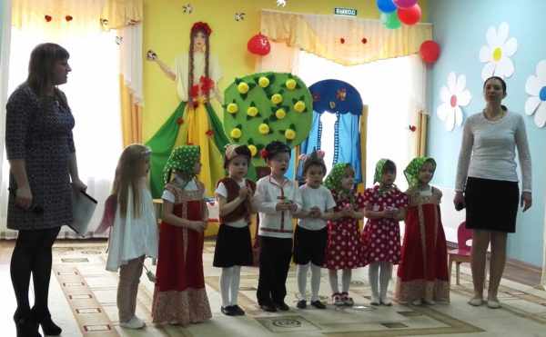 Дети в костюмах участвуют в представлении, педагоги стоят рядом