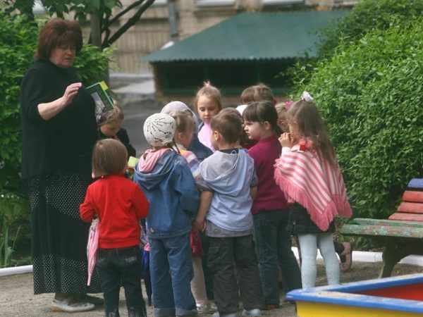 Дети на улице стоят вокруг воспитательницы