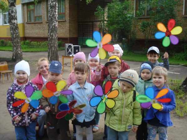 Дошкольники стоят на улице с вертушками в руках
