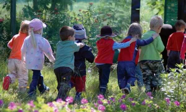 Дети идут строем по траве, руки на плечах друг друга