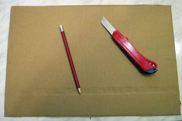 На листе плотного картона лежат карандаш и канцелярский нож