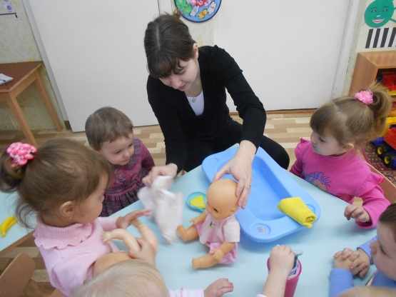 Воспитательница показывает, как мыть и вытирать куклу