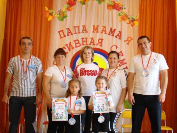Родители и дети стоят с медалями и дипломами