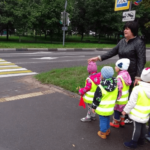 Воспитатель ведёт группу детей к пешеходному переходу