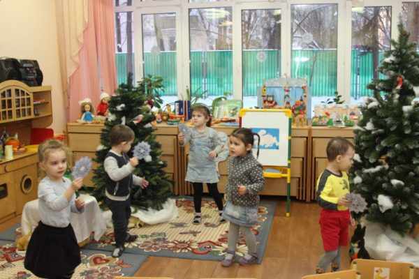Дети ищут снежинки в помещении группы с зимними декорациями