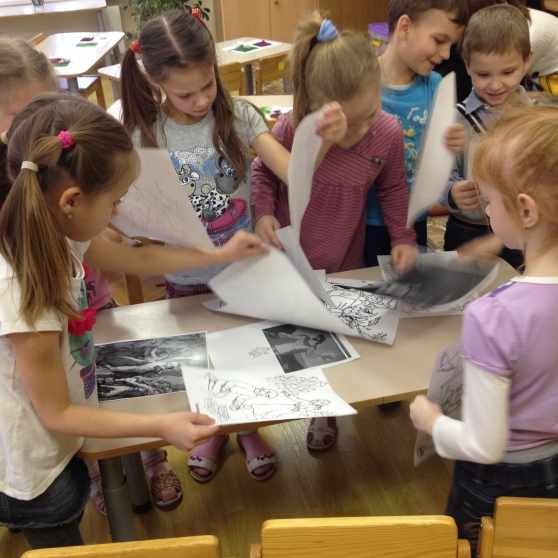 Старшие дошкольники рассматривают чёрно-белые картинки, разложенные на столе
