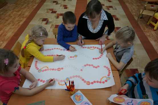 Дети вместе с воспитателем рисуют поле для настольной игры
