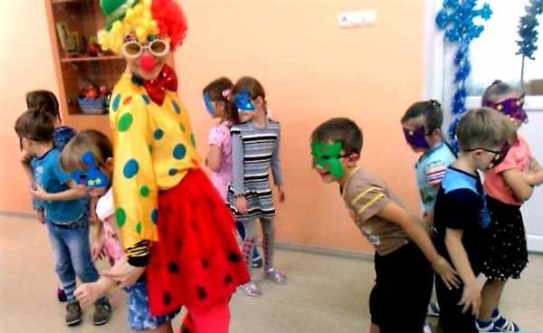 Воспитатель в костюме клоуна и дети в масках играют в подвижную игру