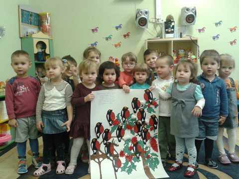 Дети держат ватман, на котором изображены деревья и стайка снегирей
