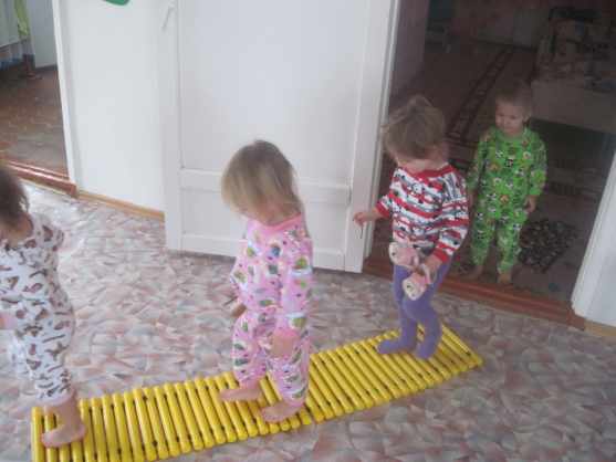 Дети в пижамах идут по массажному коврику-
