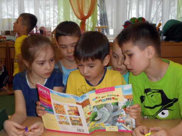 Дети читают книгу в группе