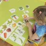 Девочка собирает разрезные картинки «Овощи» - соединяет вершки и корешки