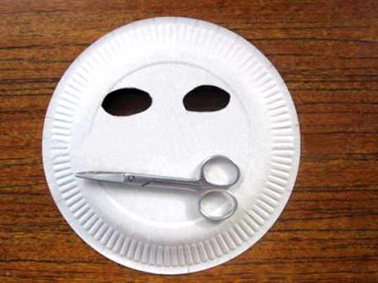 В тарелке маникюрными ножницами вырезаны отверстия для глаз