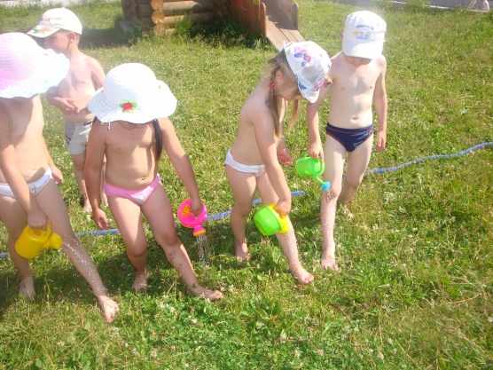 Дети в жару льют воду себе на ноги из леек