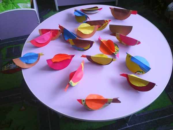 Яркие птички из бумаги на столе