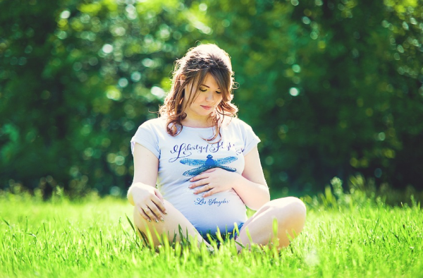 беременная сидит в позе лотоса на природе