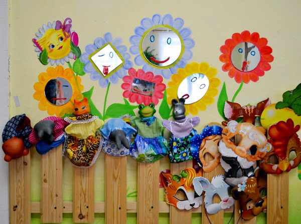 Деревянный заборчик с масками, куклами и цветами с зеркальными серединками