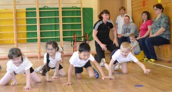 Дети выполняют физическое упражнение в спортивном зале