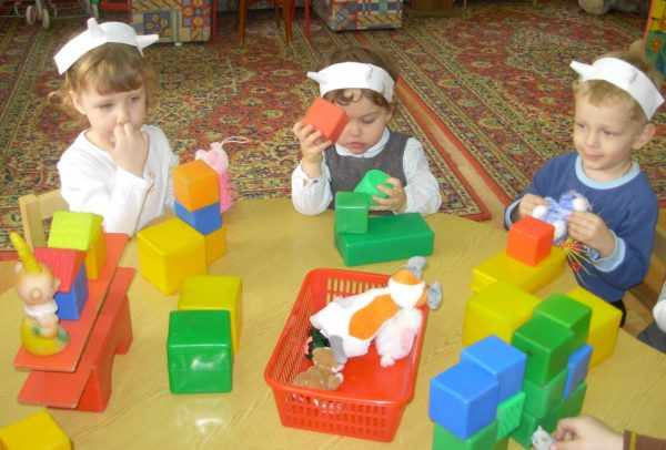 Трое детей играют с большими разноцветными кубиками