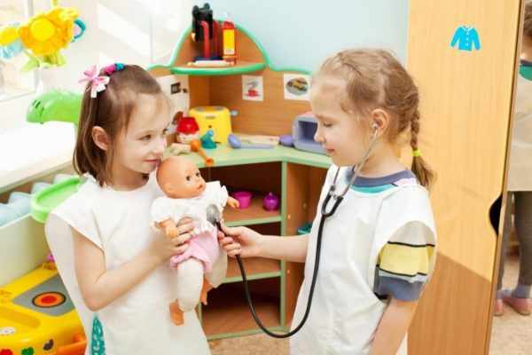 Две девочки играют в больницу с куклой