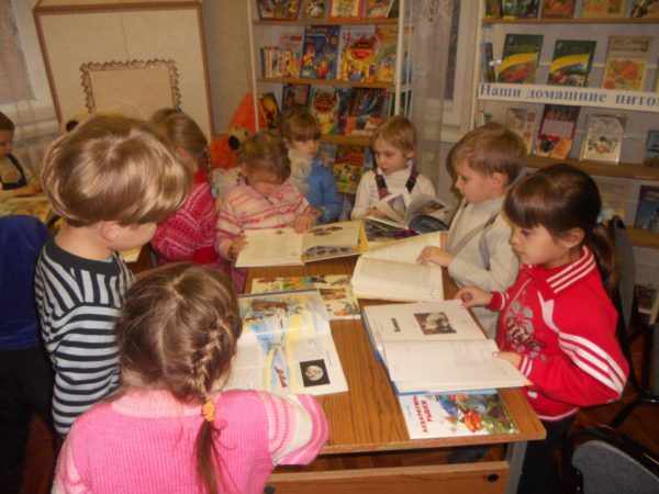 Дошкольники листают книги, разложенные на столе
