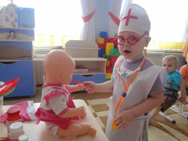 Ребёнок в роли врача играет с куклой