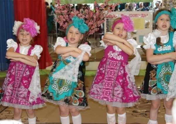 Четыре девочки в народных костюмах танцуют и поют