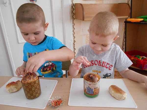 Мальчики украшают пасхальные куличи разноцветной посыпкой